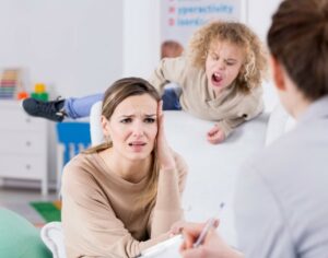 distraught mother speaks to physician as child acts out