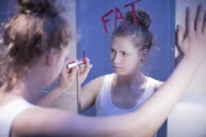 Slim girl writes "fat" on mirror