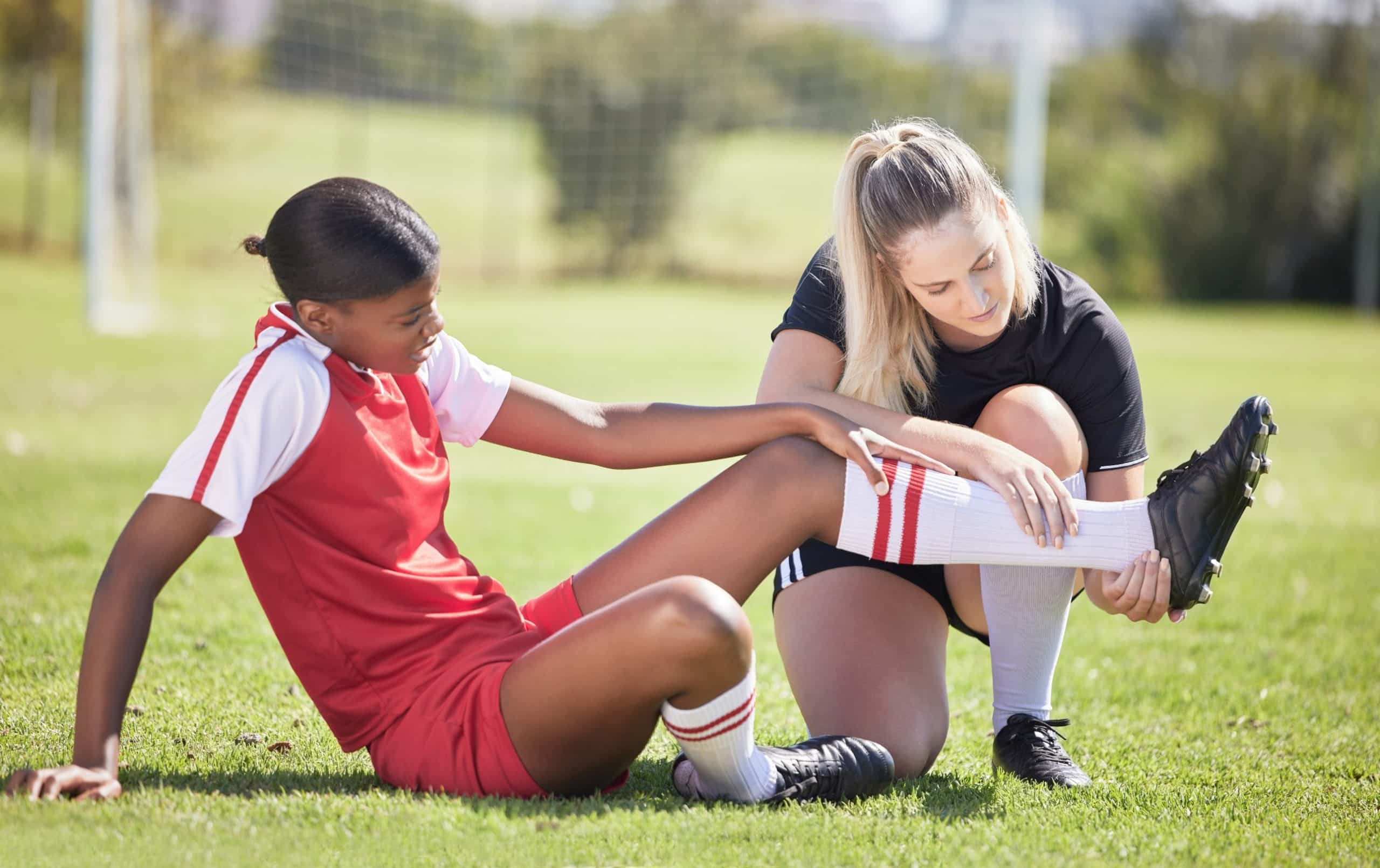 photo of coach helping injured teenage female soccer player